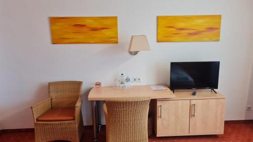 贡多夫Terra Ventura Hotel的客房设有一张书桌、一台电视和两幅画作