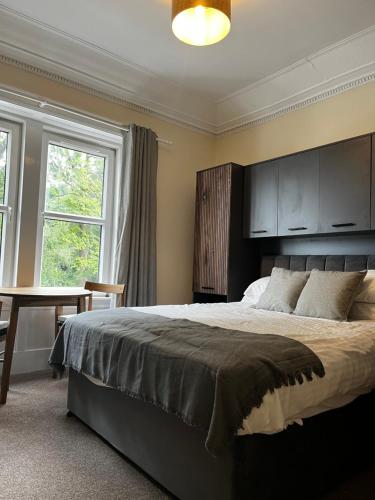 巴洛赫Norwood Guesthouse-Loch Lomond的一间卧室设有一张大床、一张桌子和窗户。