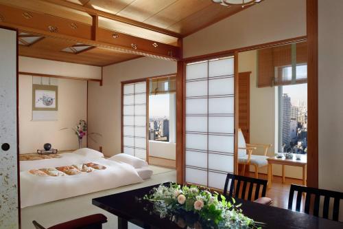 大阪大阪丽思卡尔顿酒店的一间带一张床铺和一张桌子的房间,以及一间用餐室