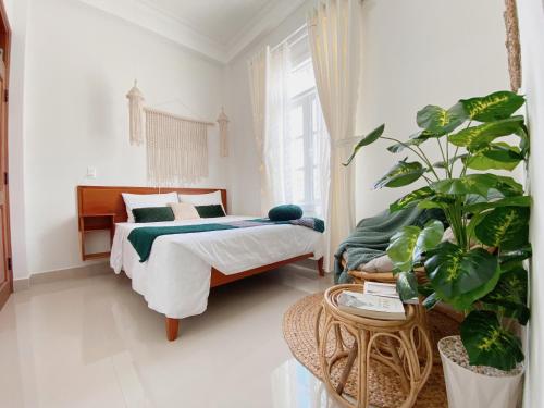 大叻Lantana Homestay的一间卧室配有一张床和盆栽植物
