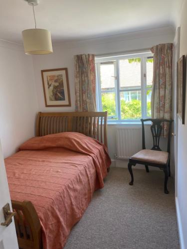 查尔顿Goodwood Rooms的一间卧室设有一张床、一个窗口和一把椅子