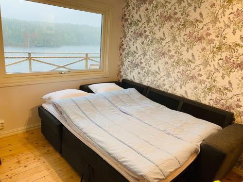 Trevligt fritidshus med stor terrasse mot sjöen的一张位于带窗户的房间的床