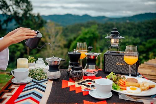 Mon Jamเดอะเนเจอร์ ม่อนแจ่ม The nature camping monjam的餐桌,餐桌上放着食物,还有人倒橙汁