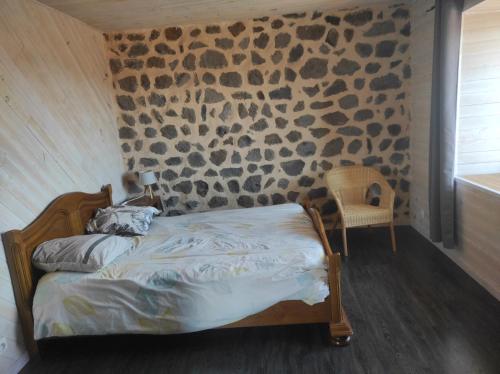 Le BrignonGite La Tourterelle的一间卧室设有一张床和石墙