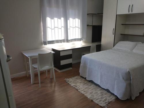 圣若泽杜斯皮尼艾斯Residencial Vitor Studio 5的一间卧室配有一张床、一张桌子和一张桌子