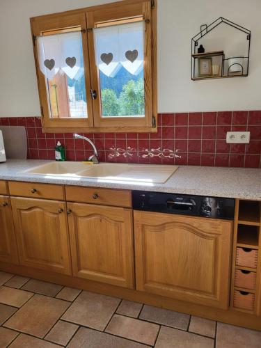 大博尔南La petite Anfiane的厨房配有木制橱柜、水槽和窗户。