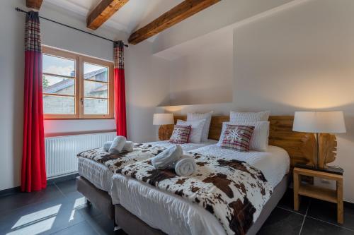 梅塔比耶Géraniums Et Neige Fraîche, Maison d'Hôtes avec Suites Haut de Gamme, Balnéo massante et Sauna privés的一间卧室配有一张带红色窗帘的大床