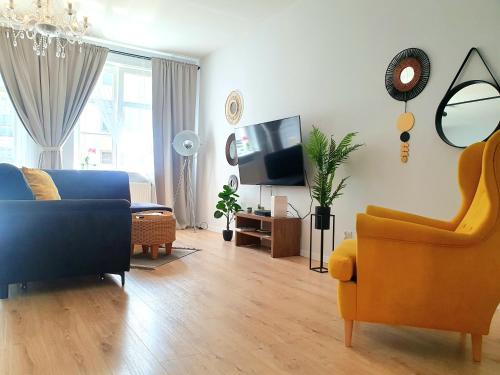 埃尔布隆格Apartament Amber Dwie Sypialnie Stare Miasto的客厅配有蓝色的沙发和黄色的椅子