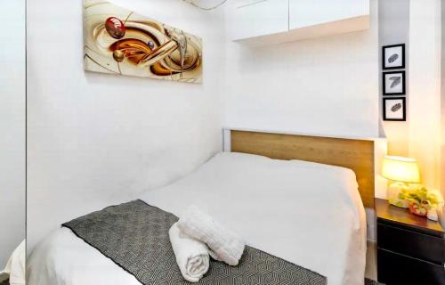 特拉维夫צימר פרטי בבוגרשוב VIp אופציה לחניה的卧室配有白色的床和墙上的绘画作品