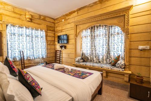 斋沙默尔Hotel Relax Inn Jaisalmer的一间卧室设有一张床和两个窗户。