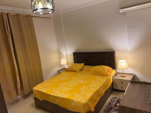 Dawwār RuḩayyimSummer vacation flat的一间卧室配有一张带黄色被子和两盏灯的床。