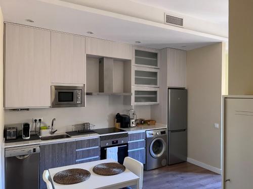 马德里Apartment in monumental square Madrid Center的厨房配有白色橱柜、桌子和水槽。