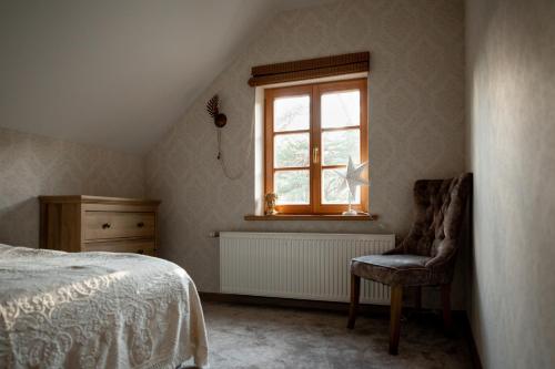 文茨皮尔斯BASH Village House的卧室配有床、椅子和窗户。