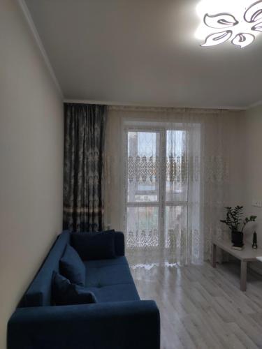 KirovoВ Астане новая комфортная квартира у реки и парка的客厅设有蓝色的沙发和窗户。