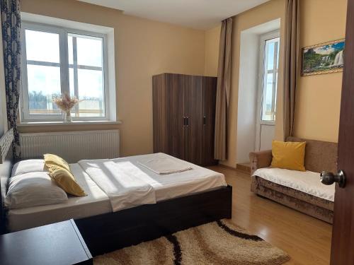 乌拉尔斯克Просторная и уютная 3х комнатная в центре!的一间卧室配有一张床、一张沙发和两个窗户。