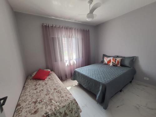 大普拉亚BEIRA MAR I - TUPI - 15 metros da praia - 2 dormitórios com VARANDA - WI FI e acomoda até 8 pessoas - ESTACIONAMENTO Gratuito的一间卧室设有两张床和窗户。