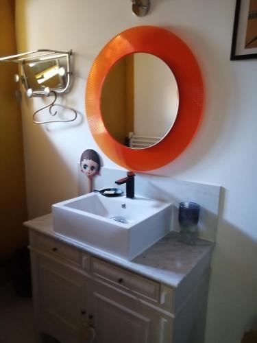 Saint-Féliu-dʼAvallMaison d'Art' lette的浴室内白色水槽上方的橙色镜子