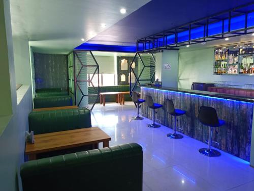 古瓦哈提Hotel Autumn Crocus的酒吧设有绿色椅子和木桌