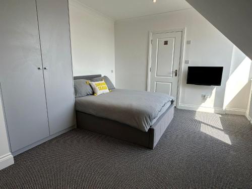 亨顿Stylish Modern, 1 Bed Flat, 15 Mins To Central London的一间卧室配有一张床,墙上配有电视