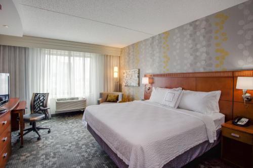法明代尔长岛/法明代尔共和国机场万怡酒店的酒店客房配有一张床、一张书桌和一台电视。