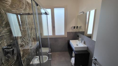 里米尼Hotel Giannini的一间带玻璃淋浴和水槽的浴室