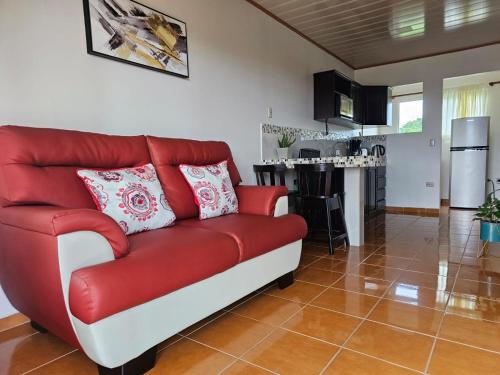 福尔图纳Volcano View Apartment的客厅里设有一张红色的沙发,配有厨房