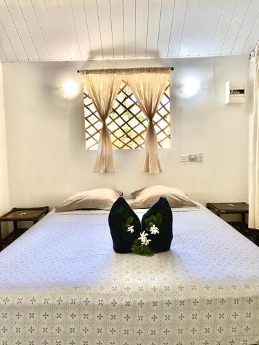 阿瓦托鲁Poe Guesthouse的一张带两个黑色枕头的床,上面有鲜花