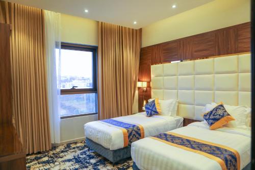 塔伊夫Oriens Hotel的酒店客房设有两张床和窗户。