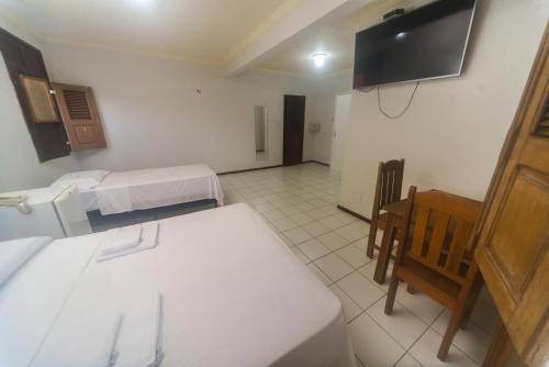 巴雷里尼亚斯Pousada Vista do Rio的客房设有两张床、一张桌子和电视。