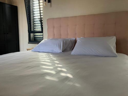 玛尔盖姆拉בסנדלים: חאן בוטיק בגולן的一张带两个枕头和窗户的大型白色床