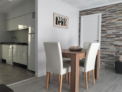 圣波拉Isla 1.1的厨房以及带木桌和白色椅子的用餐室。