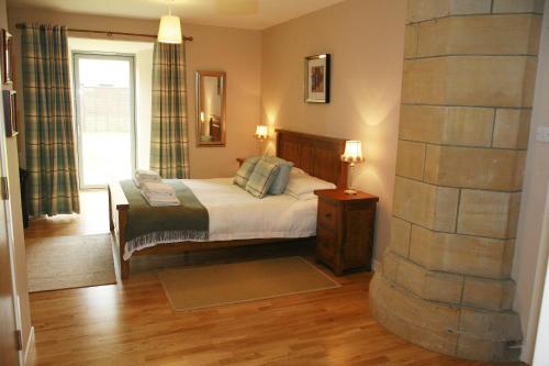 奥古斯都堡高地俱乐部修道院花园公寓的一间卧室设有一张床和石墙
