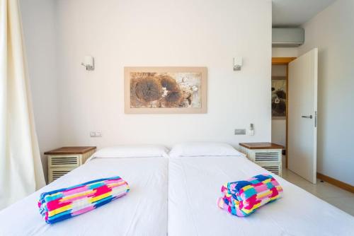 马斯帕洛马斯Villa Vista Golf Salobre - Maspalomas self-sufficient with pool heating的一张白色的床,上面有两个色彩缤纷的枕头