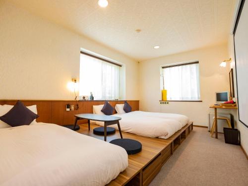 FutoWe Home Villa ～城ケ崎温泉～的酒店客房设有两张床和一张桌子。