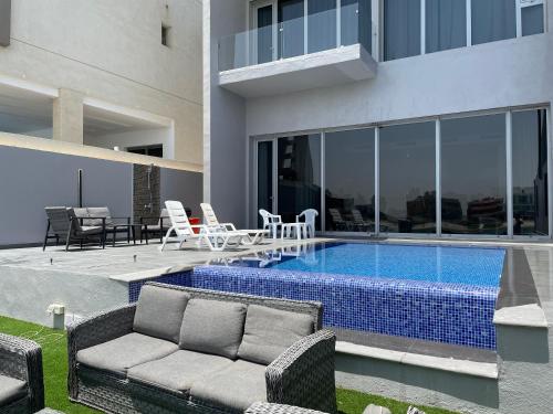 阿尔科兰Sama Chalet kuwait的房屋旁的游泳池配有长沙发和椅子