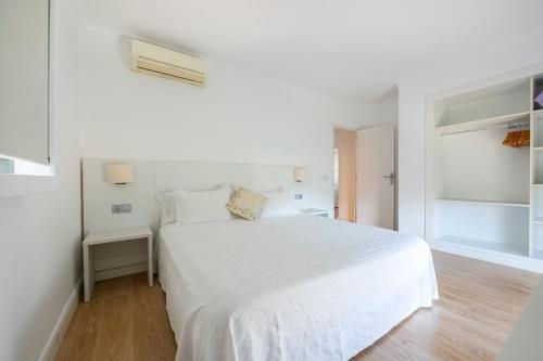 埃斯普霍斯Apartamentos Catalina的白色卧室设有白色的床和木地板