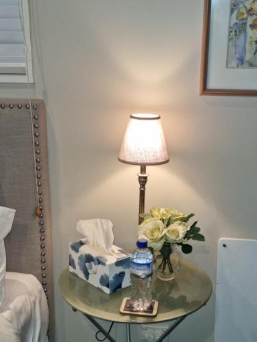 皇后镇Haven Sanctuary Suite with Private Entrance的一张桌子,配有一盏灯和一瓶水及鲜花