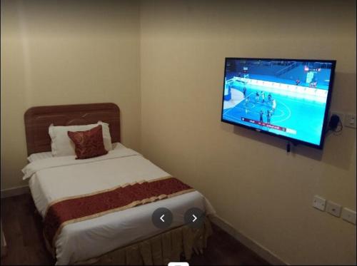 麦地那Zahret Al Madinah的一间设有床铺和墙上电视的房间
