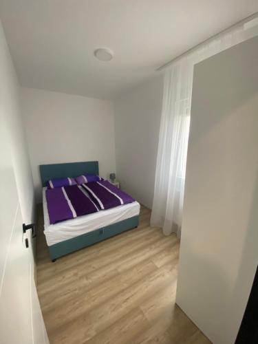 巴尼亚科维利亚查Apartman MI的一间卧室配有一张铺有木地板的紫色床单。