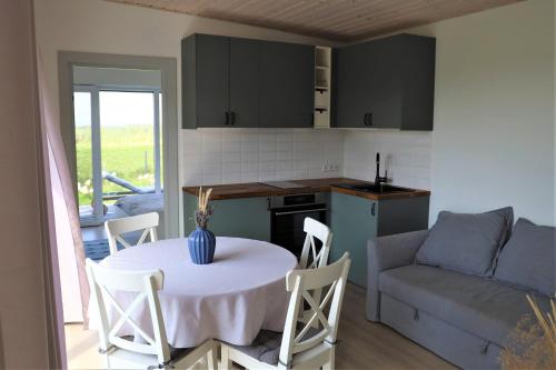 SvencelėStovyklavietė Paukščių takas的一间带桌子的客厅和一间带沙发的厨房