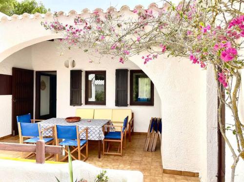卡拉莫若尔Villa Menorquina en playa的庭院配有桌椅和粉红色的鲜花。