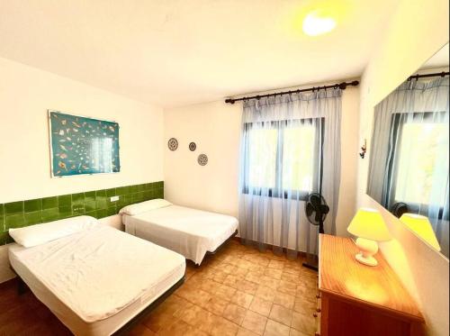 卡拉莫若尔Villa Menorquina en playa的一间卧室设有两张床、一张桌子和一个窗口。