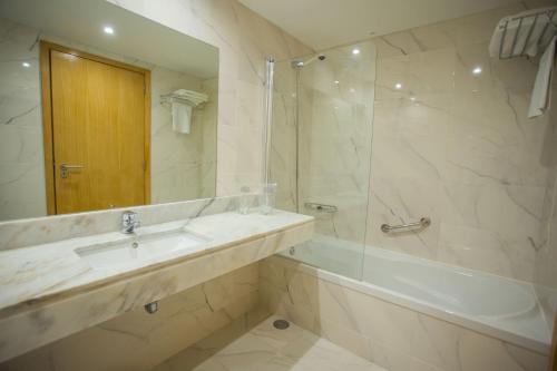 孔迪镇Hotel Brazão的一间带水槽、浴缸和淋浴的浴室