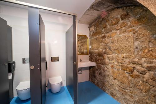 卡米尼亚Albergue Santiago de Caminha的一间带两个卫生间和石墙的浴室