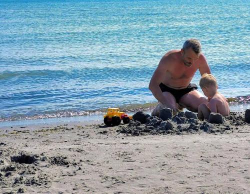 博雷Det Gamle Garnbinderi, ved Møns bedste strand.的沙滩上玩沙子的男人和男孩