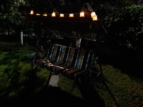阿赫洛伊къща за гости Градина的公园的长椅,上面有灯光,黑暗