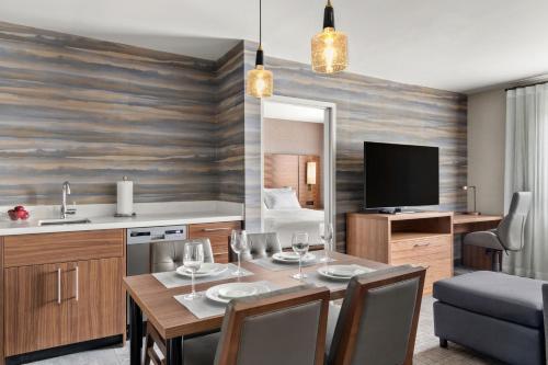拉瓦尔拉瓦尔品质套房酒店的厨房以及带桌子和电视的用餐室。