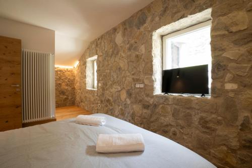 阿莱盖SnowLake Suite & Apartment的一间卧室设有石墙、一张床和电视。
