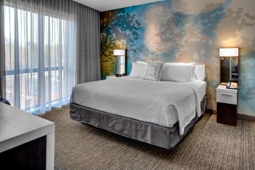 卡罗尔顿卡罗尔顿万豪万怡酒店的一间卧室配有一张大床和壁画