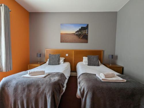 剑桥德比伯爵酒店的橙色墙壁客房的两张床